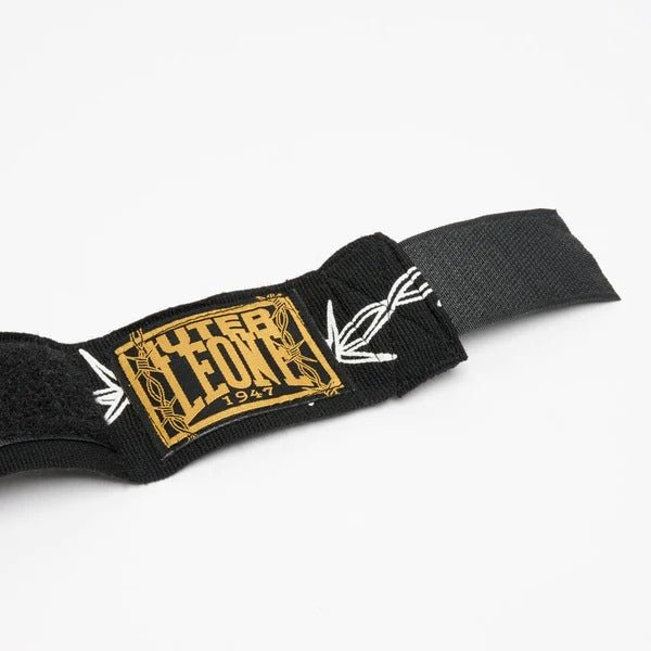 Detalle de la etiqueta tejida en oro con los logos de LEONE e IUTER en las vendas negras.