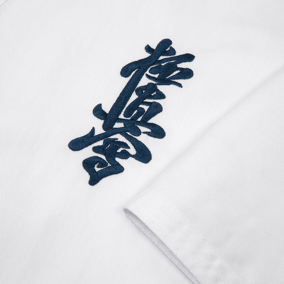Dettaglio del ricamo Kanji blu originale sul petto del Karategi Kyokushin Fujimae.