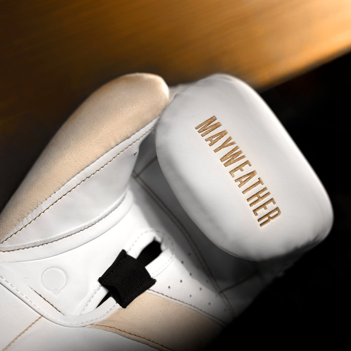 Detalle del acolchado interno y barra de agarre en ángulo de los guantes Mayweather Champ en oro blanco.