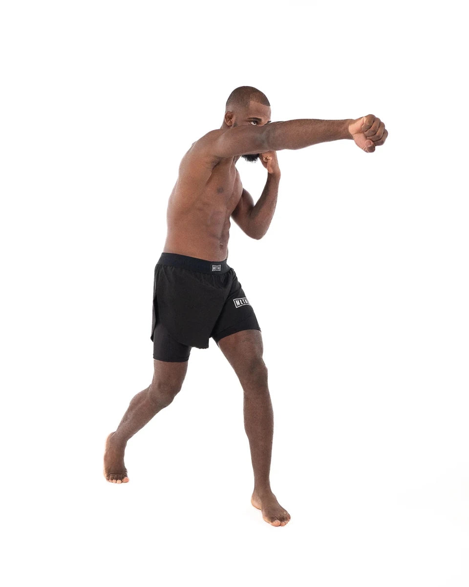 Zawodnik w akcji, ubrany w czarne spodenki 2w1 Metal Boxe, podczas techniki uderzania pięścią