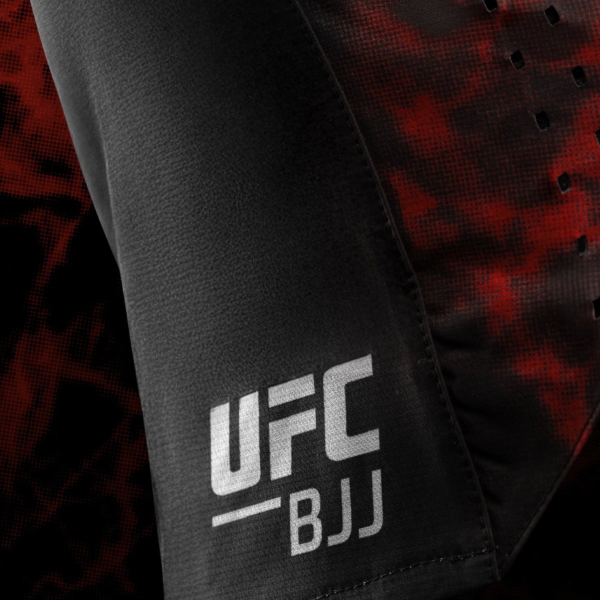 Nahaufnahme des seitlichen UFC BJJ-Logos auf schwarzen und roten Grappling-Shorts für Damen