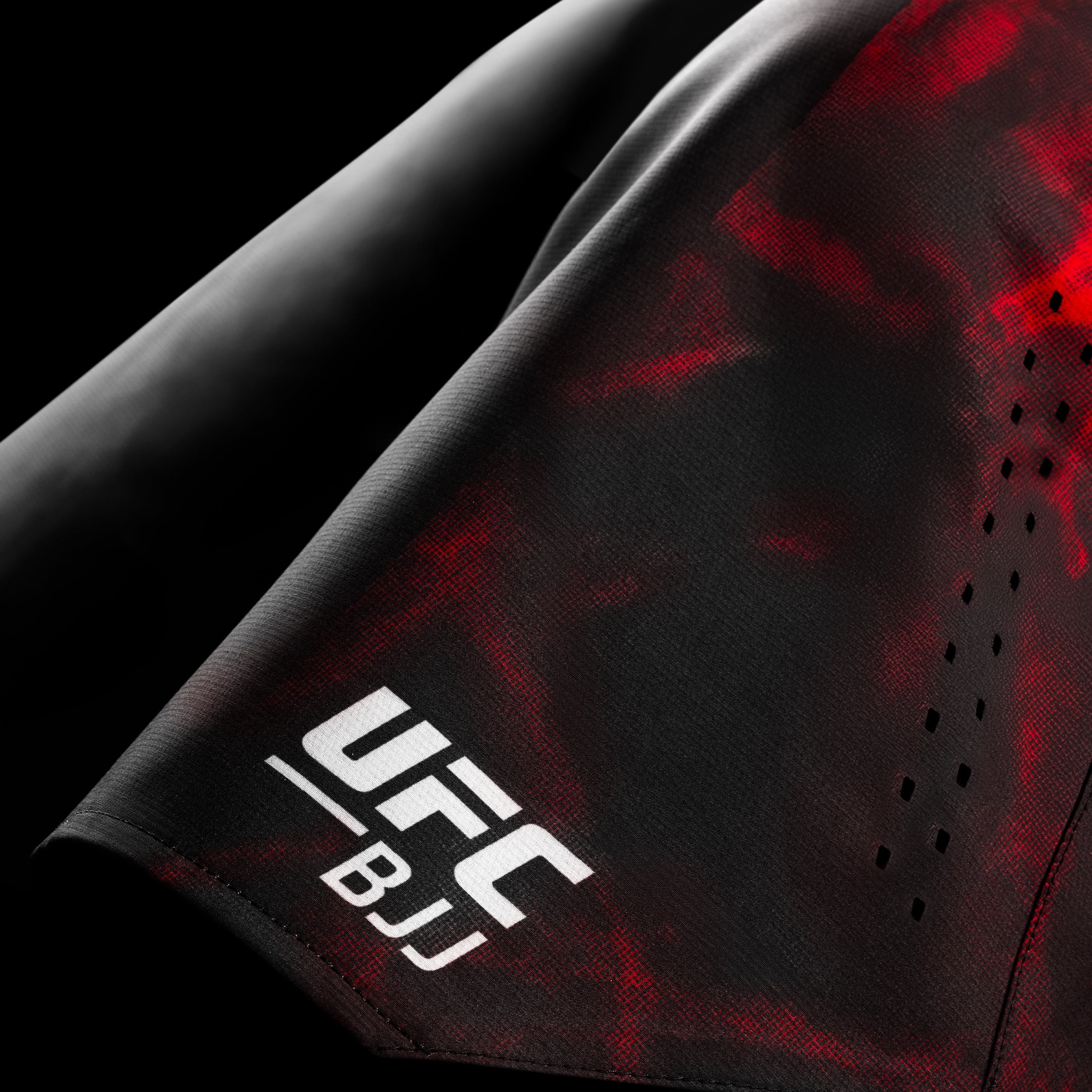 Primo piano della grafica ufficiale UFC BJJ stampata sui pantaloncini da grappling neri e rossi