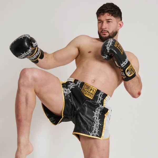 Sportowiec w pozie kopnięcia Muay Thai pokazujący elastyczność spodenek z drutu kolczastego