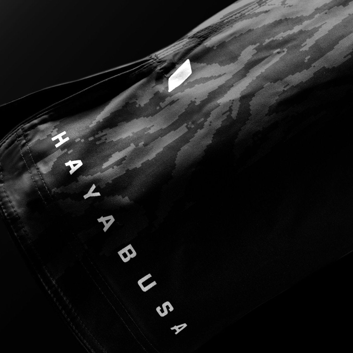 Nahaufnahme des Hayabusa-Markenschriftzugs auf dem Bein der schwarzen Apex 3/4-Shorts