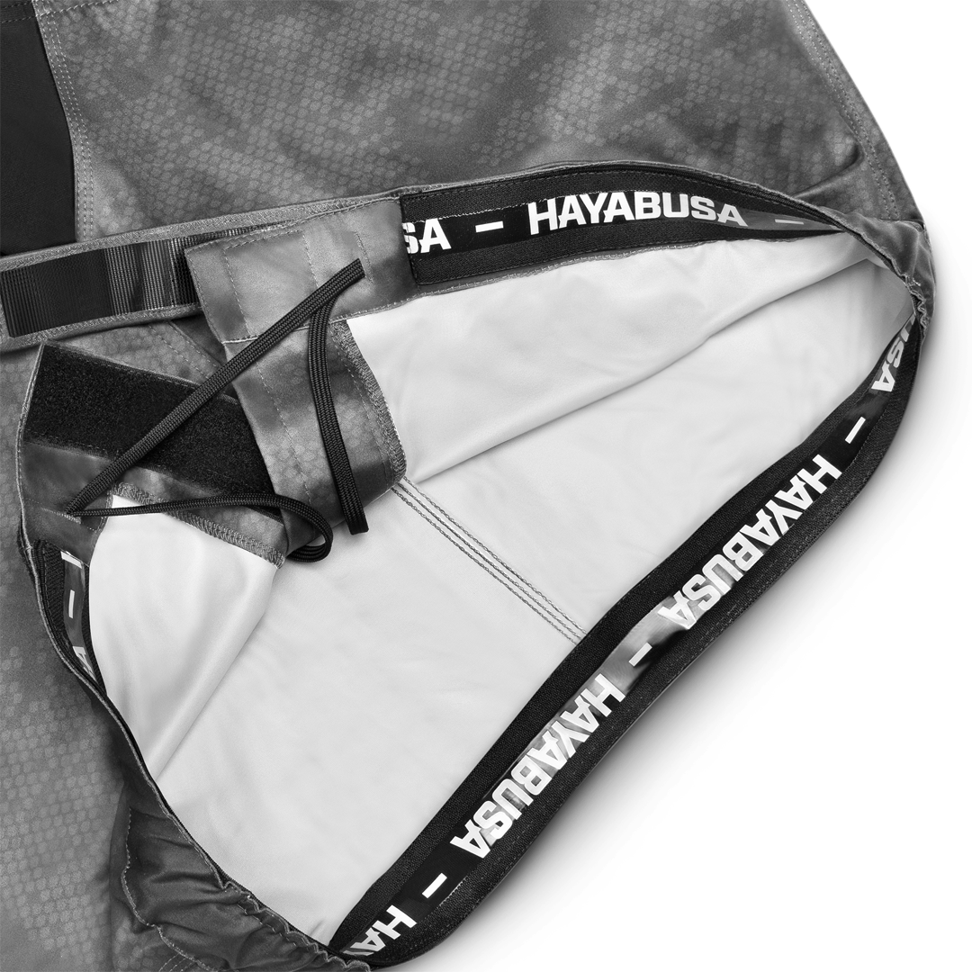 Primo piano del sistema di chiusura e del grip in silicone all'interno del girovita dei pantaloncini grigi