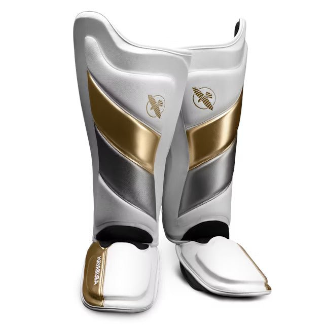 Coppia di parastinchi Hayabusa T3 Striking bianco e oro per kickboxing e MMA, vista frontale