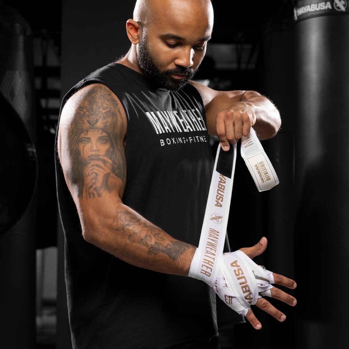 Venda técnica con vendas Mayweather Deluxe blancas y doradas para protección de nudillos y muñecas.
