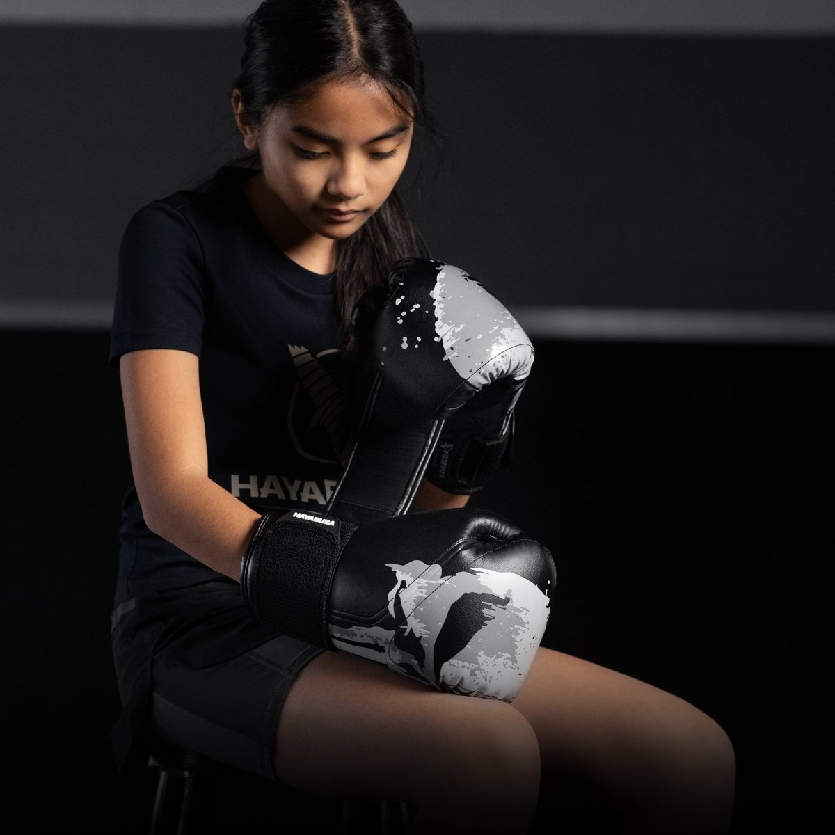 Uma garotinha usando luvas de boxe pretas Hayabusa Marvel Punisher na posição de guarda