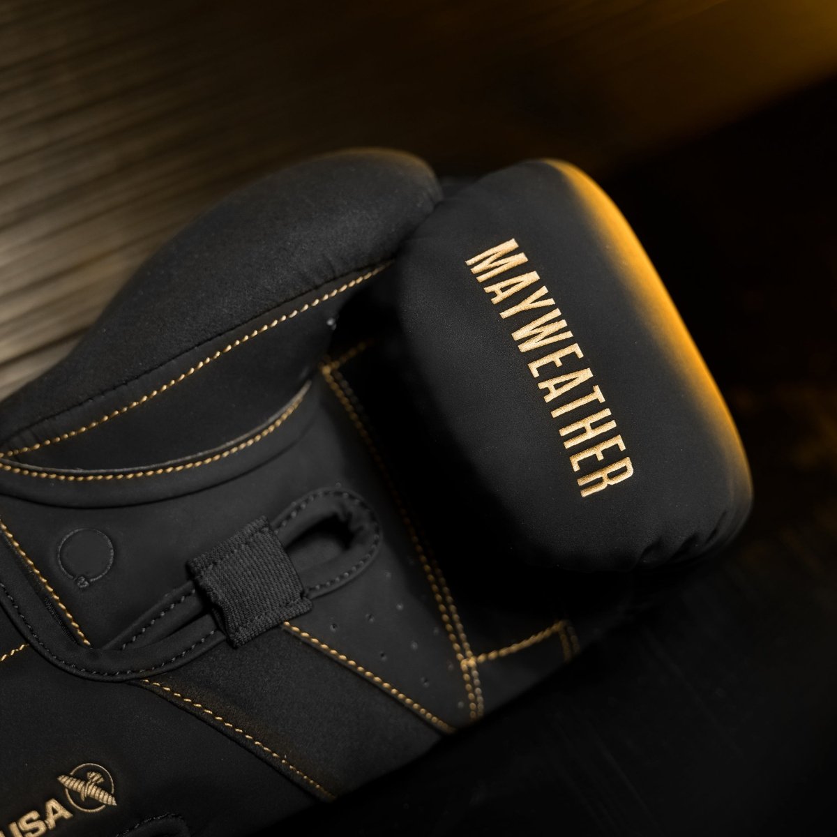 Detalle del acolchado interno y barra de agarre en ángulo de los guantes Mayweather Champ en oro negro.