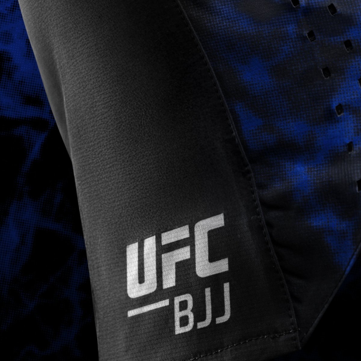 Seitliches Detail des offiziellen UFC BJJ-Logos, das auf die schwarz-blauen Damenshorts gedruckt ist