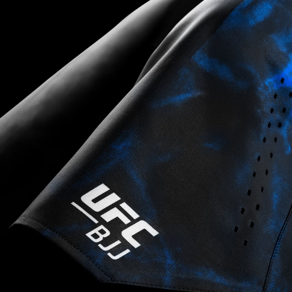 Detalle del logotipo y gráficos de UFC BJJ en los pantalones cortos de competición negros y azules.