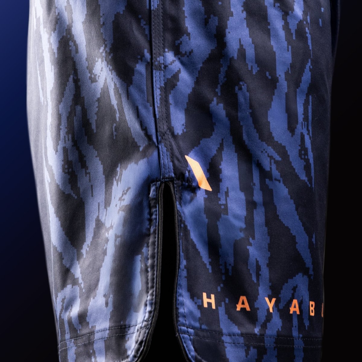 Vista lateral do short azul Hayabusa Apex Mid-Thigh MMA com detalhes de ventilação para máxima mobilidade