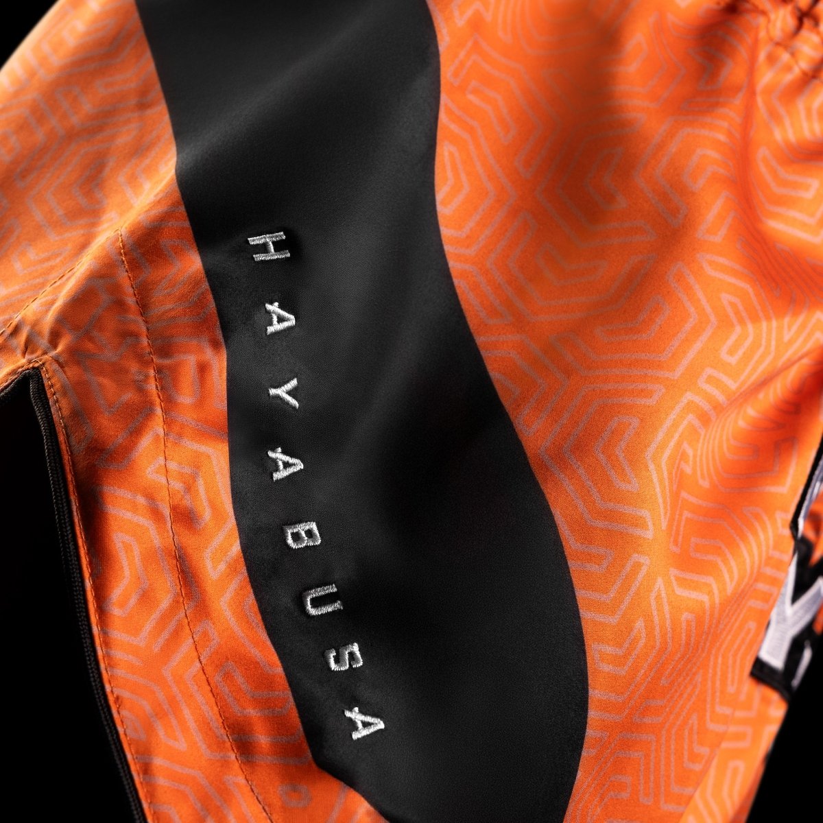 Detalle del acabado brillante y resistencia del tejido del pantalón corto naranja Hayabusa Core