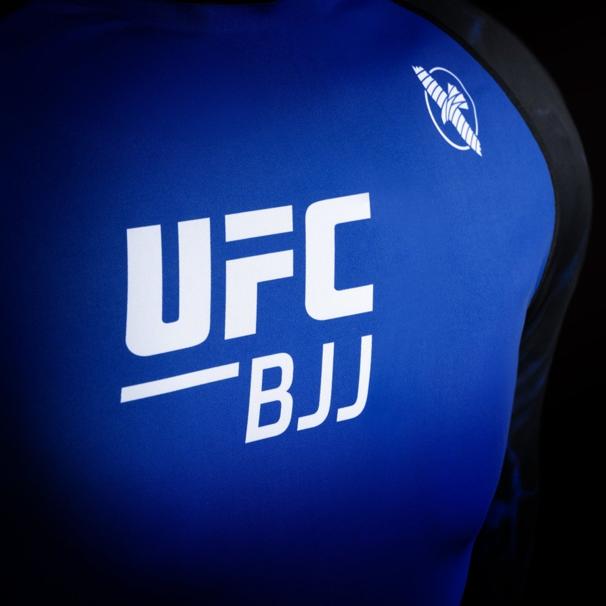 Detail logo UFC pada Rash Guard kompetisi berwarna hitam dan biru, detail kain dengan ketahanan tinggi